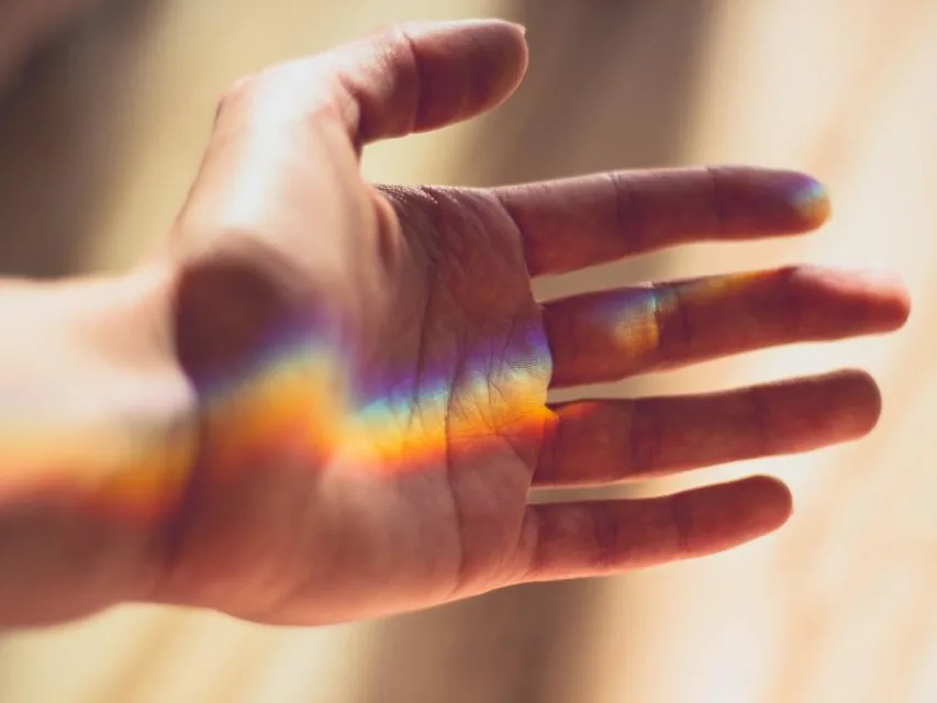 Une main ouverte que traverse un arc-en-ciel de lumière